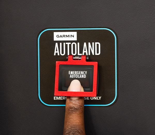 A persons finger pressing the emergency Autoland button